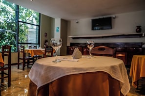 A dining table with a white tablecloth, two wine glasses, and a menu. - Hotel Europa Iquitos (Iquitos)