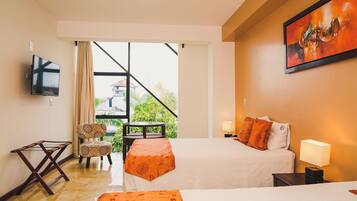 Een hotelkamer met een bed, een televisie, een stoel, een klein tafeltje en een balkon met uitzicht.
