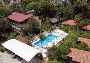 Una piscina al aire libre, sombrillas, sillones reclinables de piscina