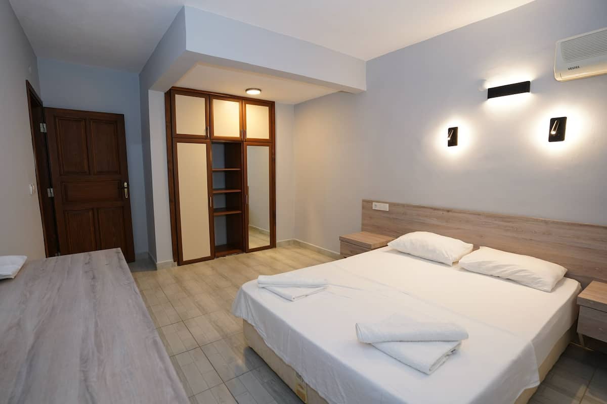 Ein Schlafzimmer mit Bett, Nachttischen, einem Kleiderschrank und einer Wand-Klimaanlage.