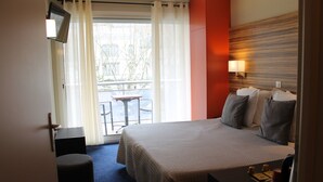 Hotellihuone, jossa on sänky, työpöytä, tuoli, televisio ja näkymä ulos.
