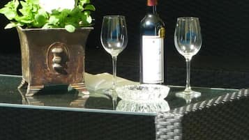 Een tafel met een fles wijn, twee glaasjes en een bloempot.