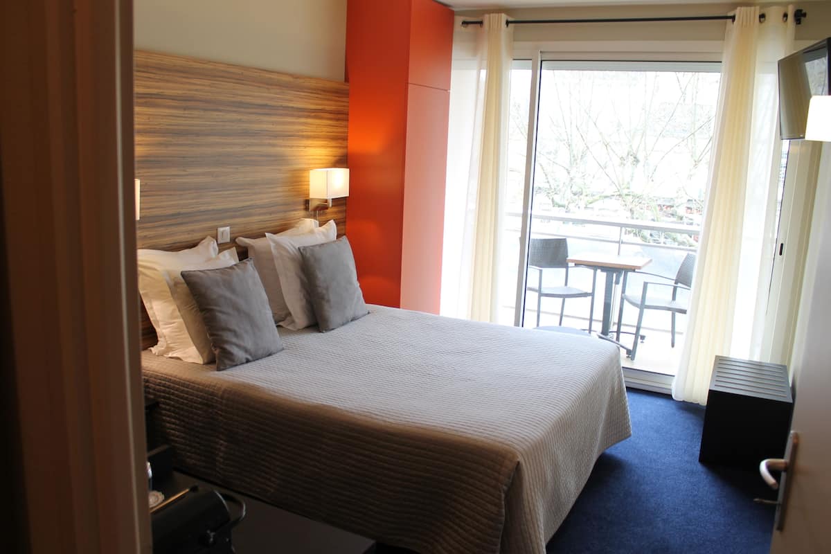 Ein Hotelzimmer mit Bett, Schreibtisch und Blick ins Freie.