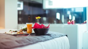 A neatly made bed with a breakfast tray, a glass of orange juice, and a vase with flowers. - Anka City (Ankara)