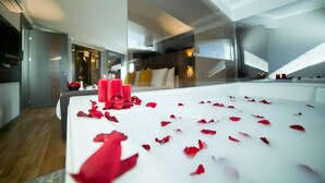 A modern hotel room with a large bed, a glass partition, and a view of the city. - Anka City (Ankara)