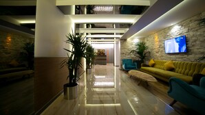 A modern lobby with a high ceiling, a stone wall, a flat-screen TV, and a yellow sofa. - Anka City (Ankara)