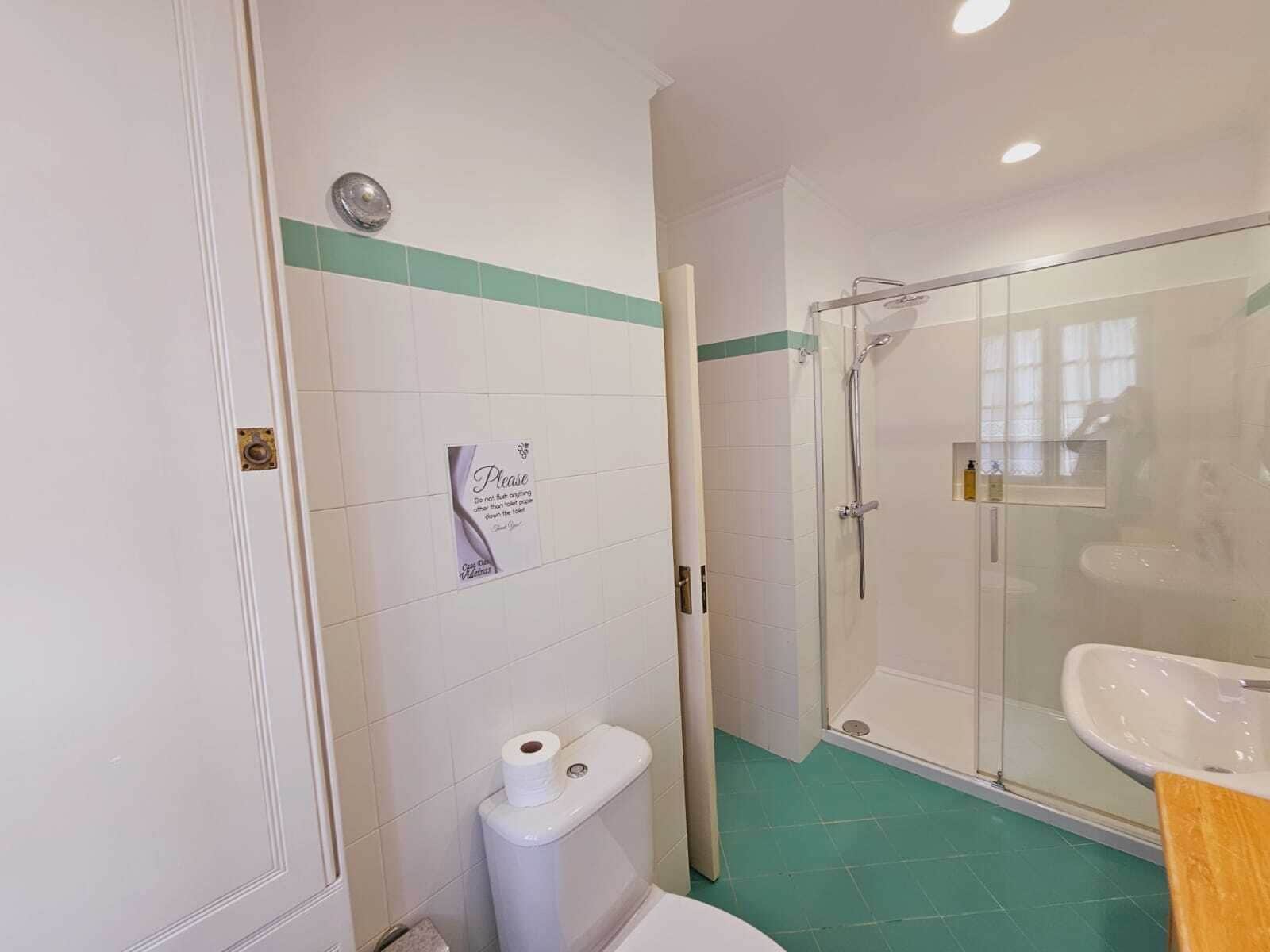 A bathroom with a toilet, a shower, and a sink.