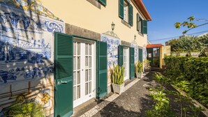 A narrow cobblestone path flanked by buildings with green shutters and blue and white decorative tiles. - Casa das Videiras (Porto Moniz)