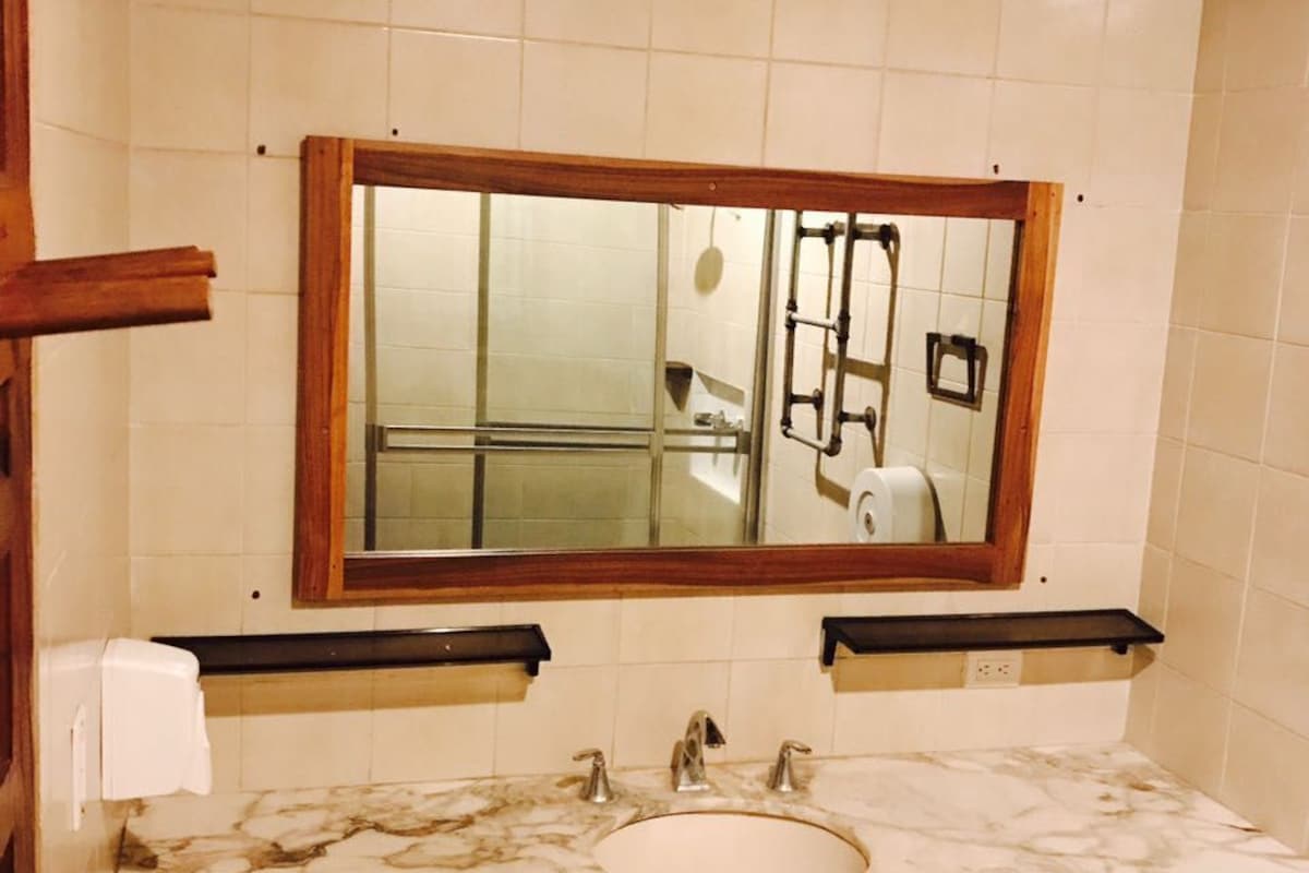 A bathroom with a marble sink, wooden vanity, and a mirror with a wooden frame.