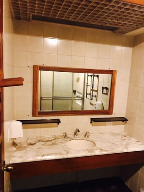 Une salle de bain avec un lavabo en marbre, un miroir encadré en bois et un porte-serviettes.