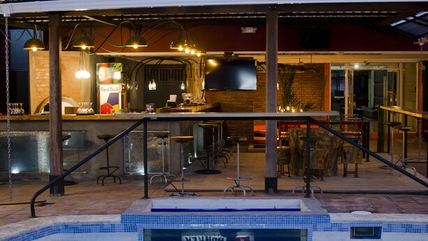 A bar area with a pool, bar stools, and a Red Bull advertisement. - Pachamama - Hotel - Hostel (Managua)