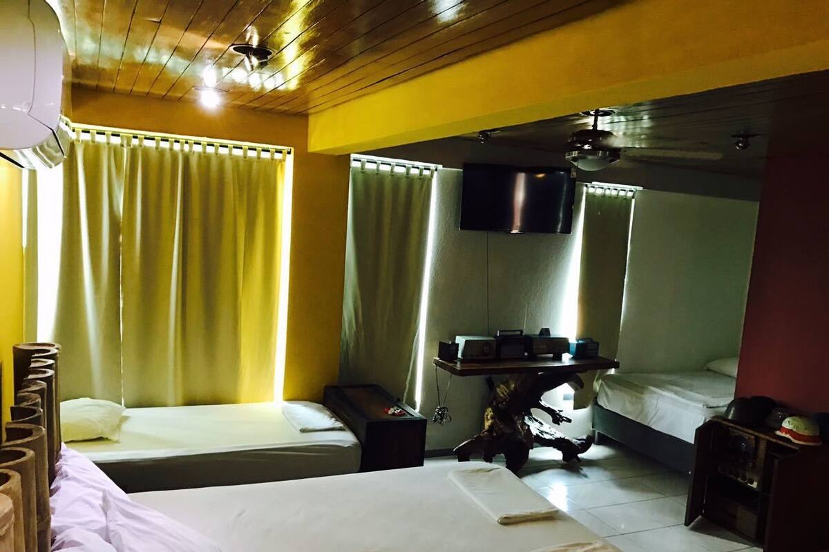 A hotel room with two beds, a small table with a radio, and a mirror.