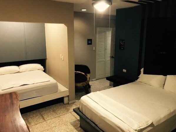 A hotel room with two beds, a desk, and a chair. - Pachamama - Hotel - Hostel (Managua)