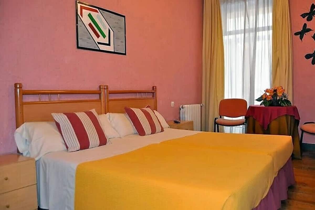 Un dormitorio con una cama de madera, una mesita de noche, una silla, una mesa con flores y una pared con diseño de mariposas.