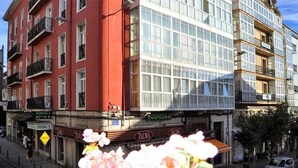 A multi-story building with a red facade and a corner shop with a sign reading "HOSPEDAJE BOTIN". - Hospedaje Botín (Santander)