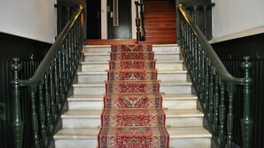 A staircase with ornate railings and a patterned carpet. - Hospedaje Botín (Santander)