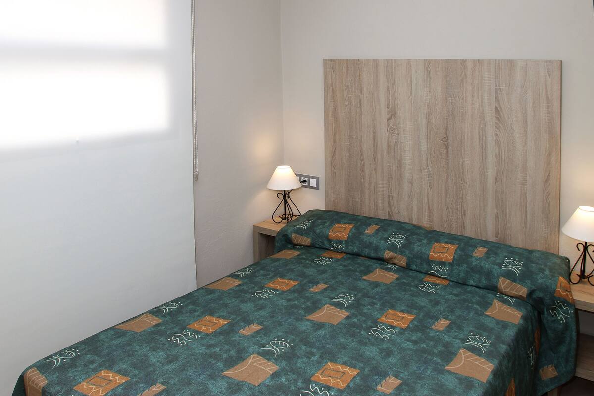 A bedroom with a bed, two bedside tables, and a headboard.