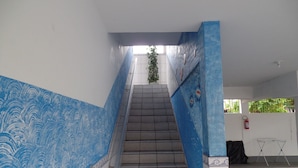 Eine Treppe mit blauen Wandmustern, einem gefliesten Boden und einem Feuerlöscher an der Wand.