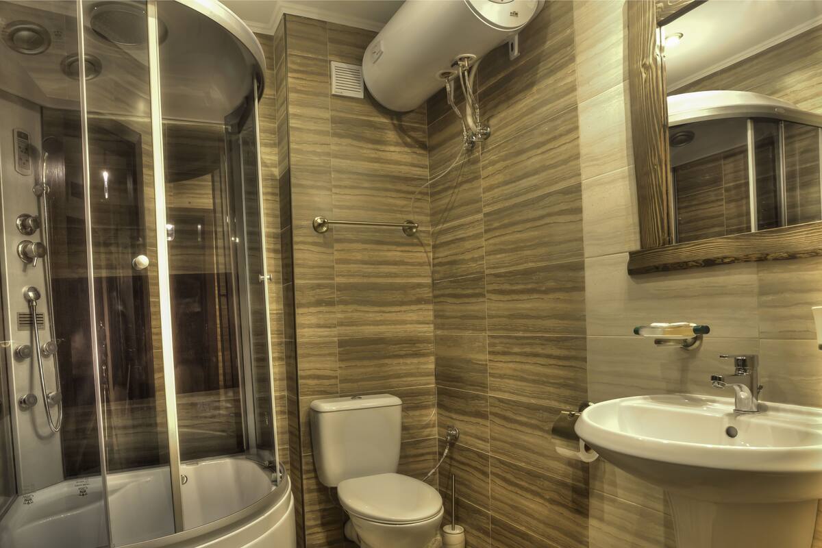 A modern bathroom with a glass-enclosed shower, a toilet, and a sink.