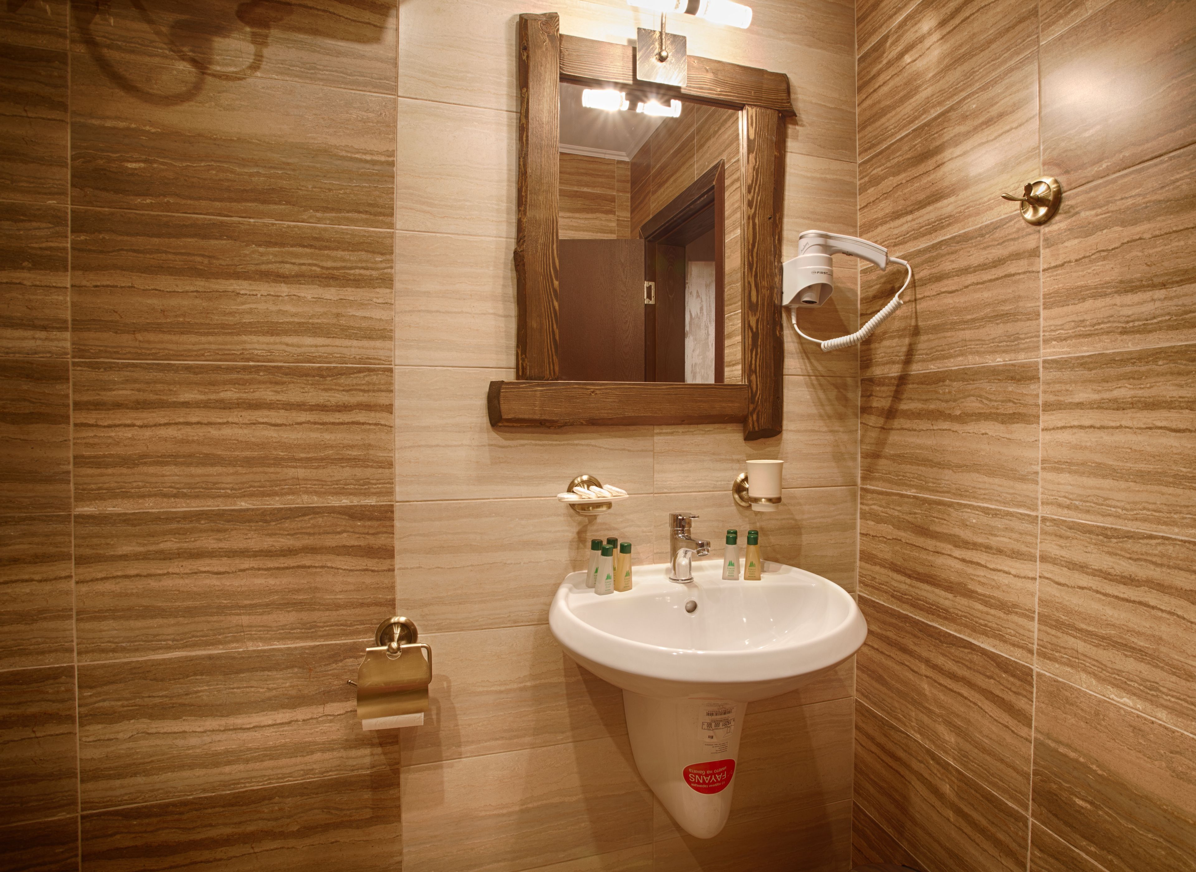 Un baño con lavamanos blanco, espejo y dispensador de toallas.