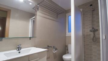 Un baño moderno con lavamanos, espejo y ducha blancos.