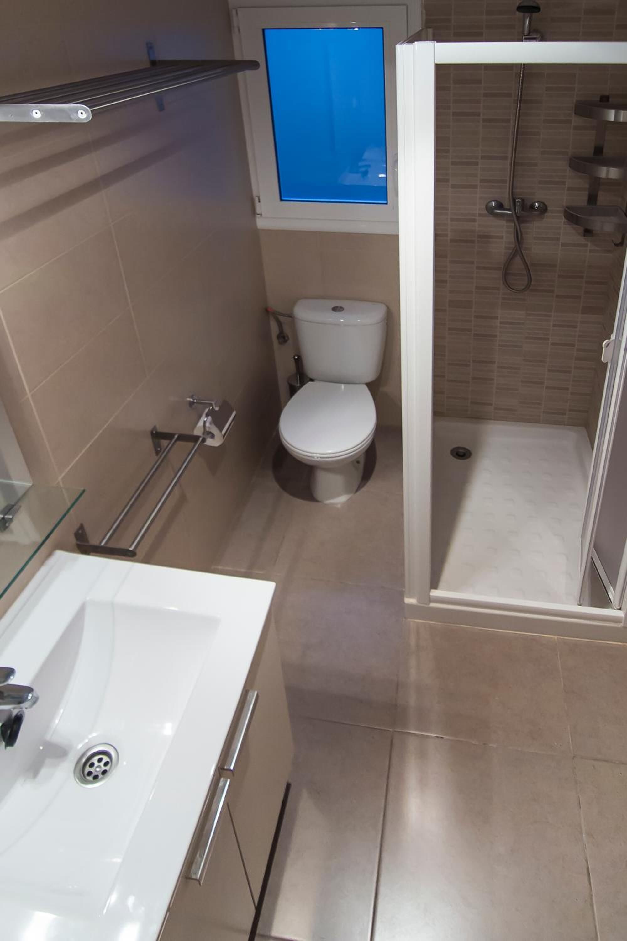 Un bagno con un WC, una doccia e un lavandino chiuso con vetro.