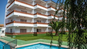 Un hôtel à plusieurs étages doté de balcons, d’une piscine et d’une pelouse bien entretenue.