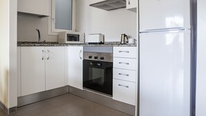 Une cuisine avec des meubles blancs, un four à micro-ondes, un grille-pain, une bouilloire et un réfrigérateur.