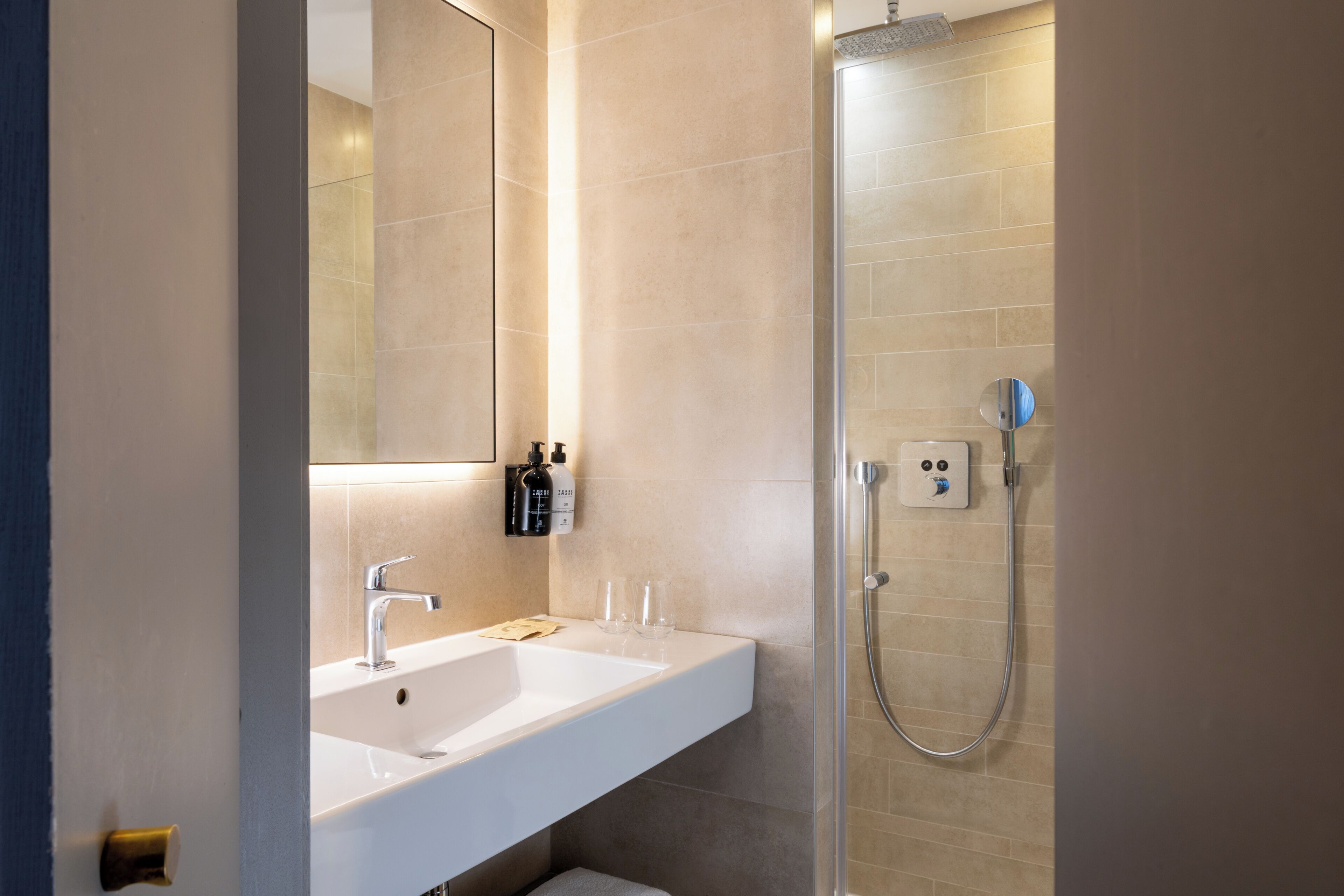 A modern bathroom with a white sink, mirror, and shower.