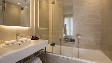 A modern bathroom with a large mirror, two sinks, a bathtub, and a shower.
