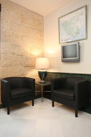 A room with two black armchairs, a lamp, a television, and a map on the wall. - Hostal La Janda (Vejer de la Frontera)