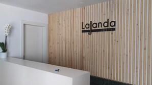 A reception desk with a wooden panel wall behind it, displaying the name 'Lajanda HOSTAL'. - Hostal La Janda (Vejer de la Frontera)