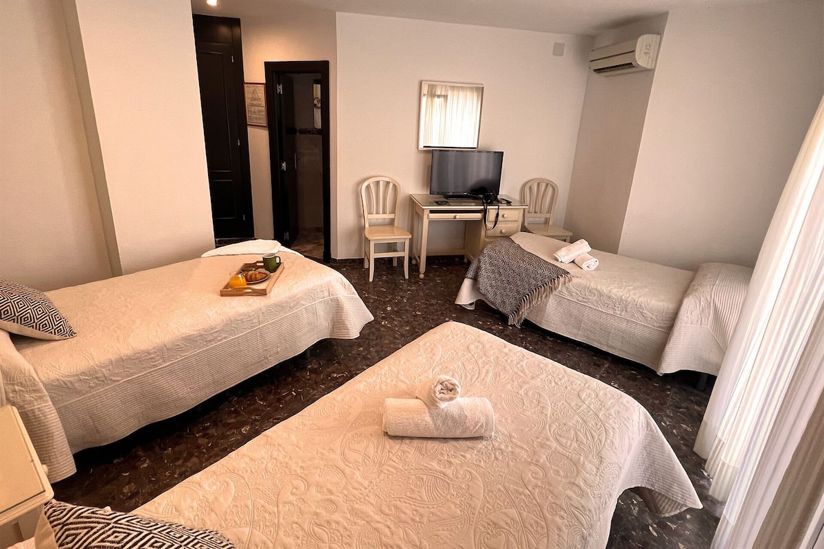 A hotel room with two single beds, a desk with a computer, a chair, and a TV.