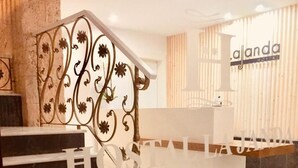 A hotel reception area with a marble staircase, a reception desk, and a wall with the hotel's name. - Hostal La Janda (Vejer de la Frontera)