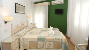 A neatly arranged hotel room with a bed, bedside table, lamp, and a television on the wall.