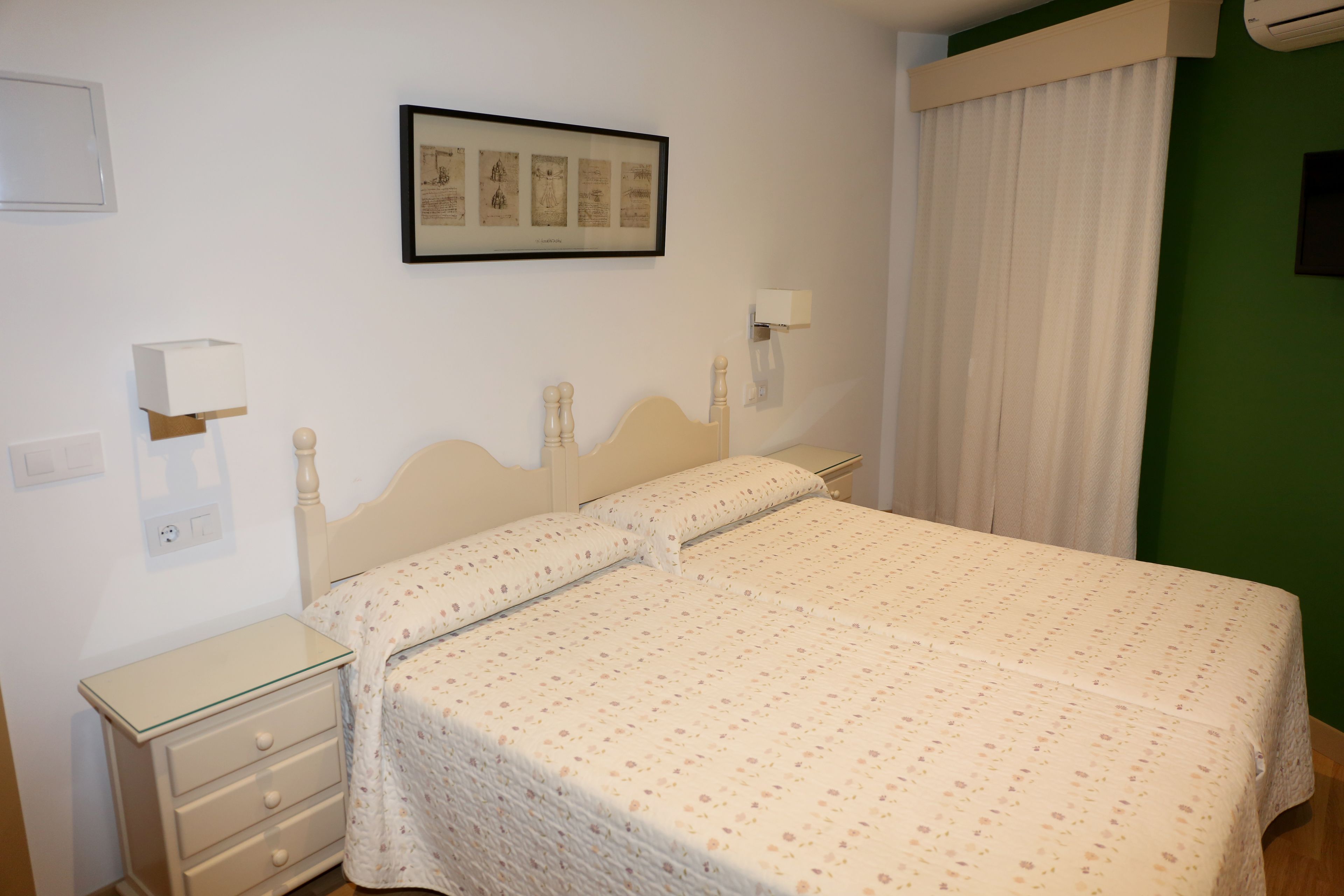 Una camera da letto con un letto, comodini, un quadro appeso al muro e una finestra con tende.