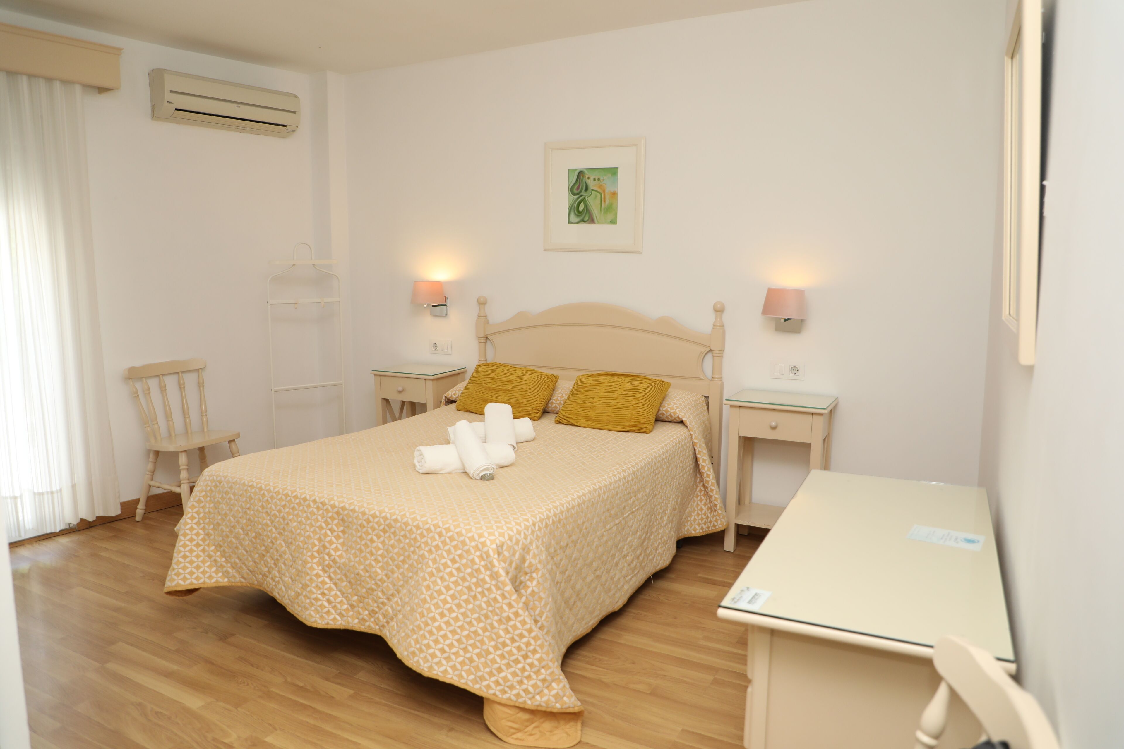 Une chambre à coucher bien rangée, avec un lit, des tables de chevet, un bureau et une chaise.
