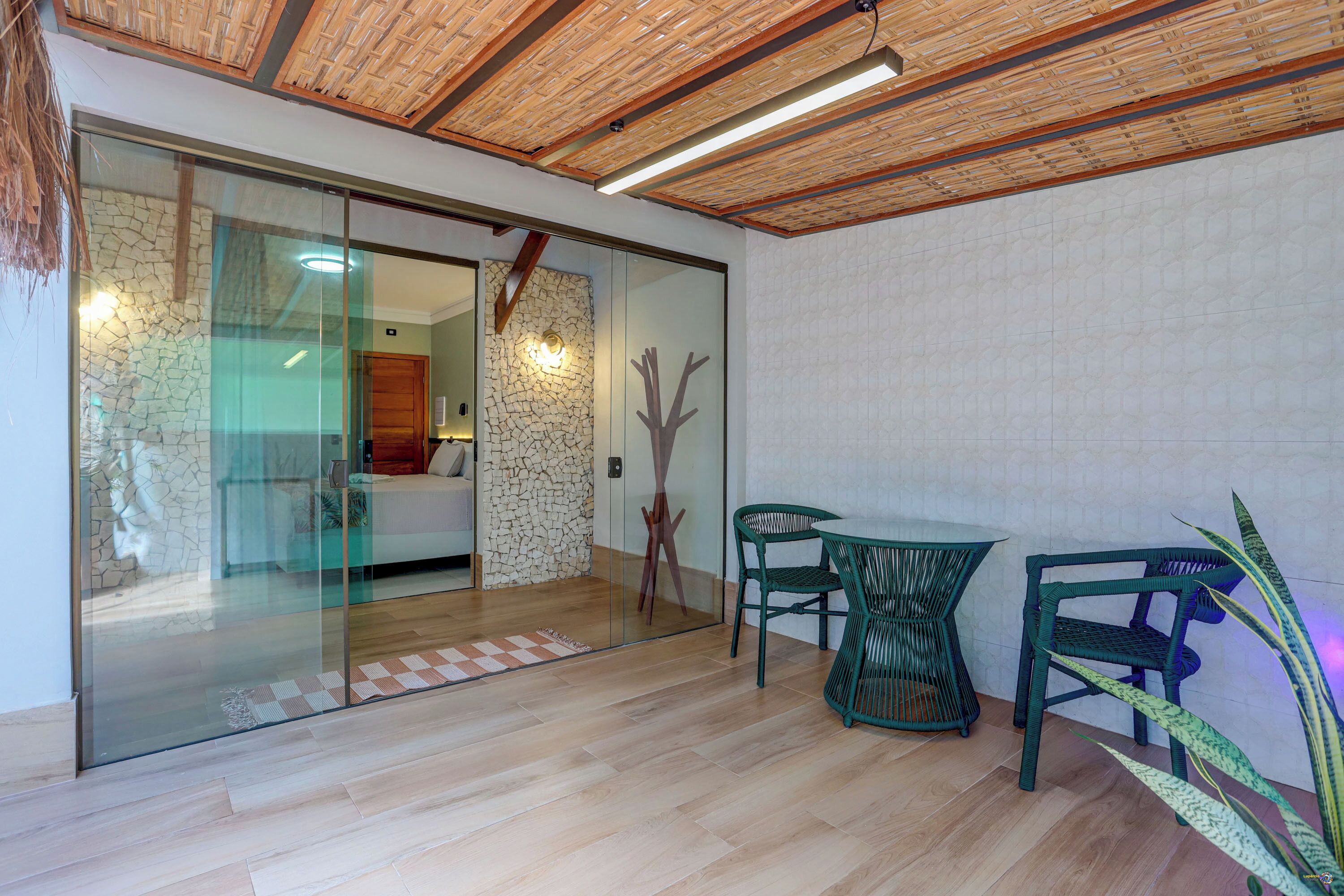 A modern interior with a glass partition, wooden flooring, and a dining area with green chairs.