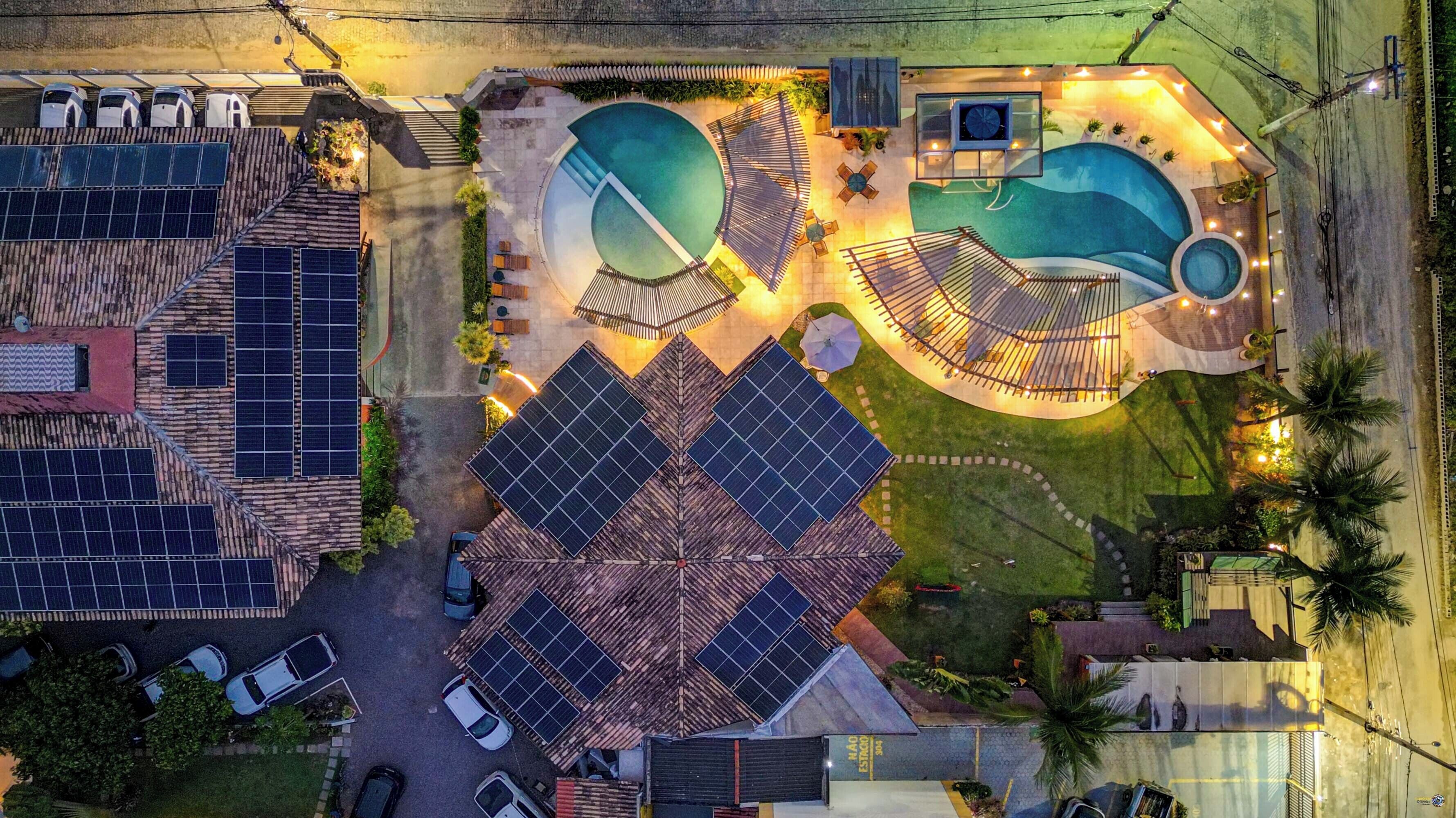 Vue aérienne d’une propriété dotée de plusieurs piscines, de panneaux solaires et d’un espace de stationnement.