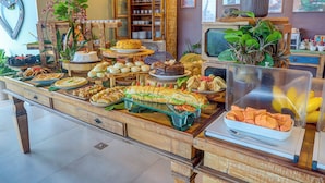 A buffet with various food items, a wooden cabinet, and a television. - Pousada Praia Bela (Ilhéus)