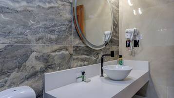 Un baño con un lavamanos blanco, un espejo, un dispensador de toallas y un dispensador de jabón.