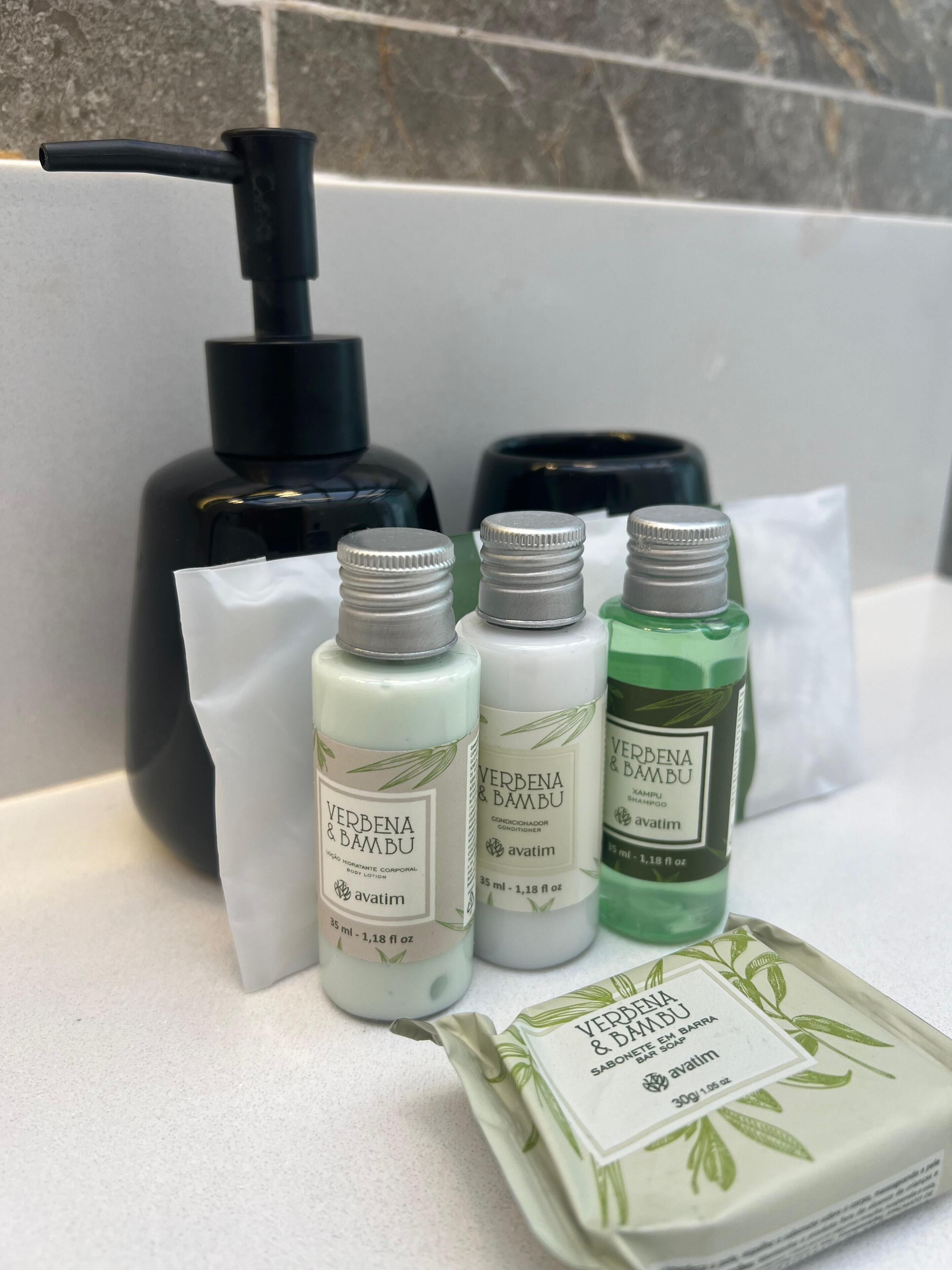 Un baño con un dispensador negro, tres productos de Verbena y Bambú, y un jabón en barra.