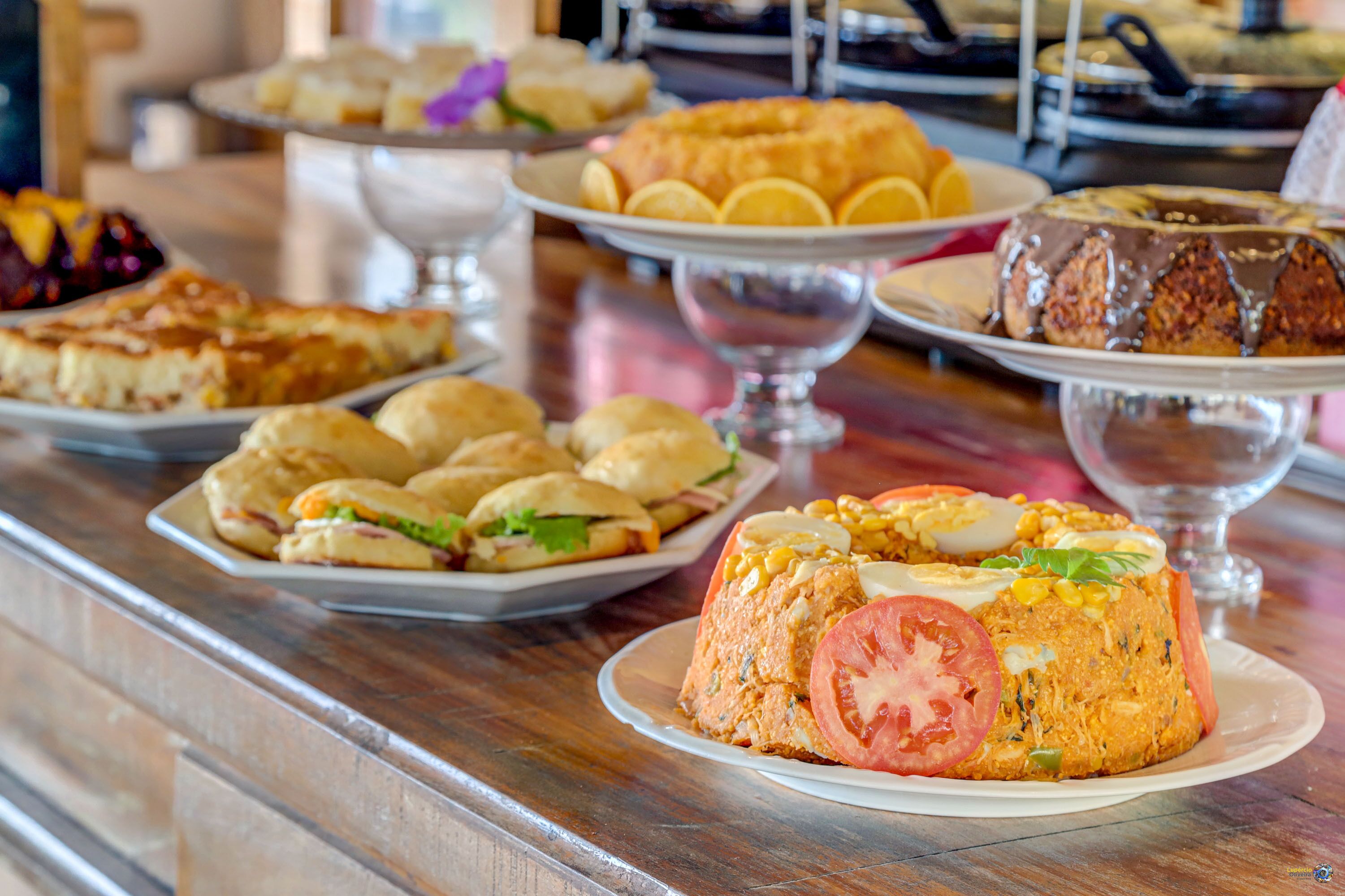 A buffet with various dishes including a layered casserole, sandwiches, and a dessert cake.