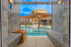 A pool area with a pergola, lounge chairs, and a wooden bench. - Pousada Praia Bela (Ilhéus)