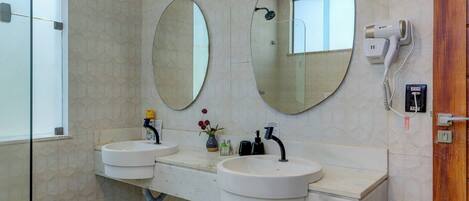 A bathroom with two sinks, a hairdryer, and a mirror.