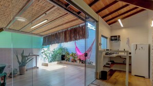 A modern kitchen with a microwave, refrigerator, and wooden beams on the ceiling. - Pousada Praia Bela (Ilhéus)