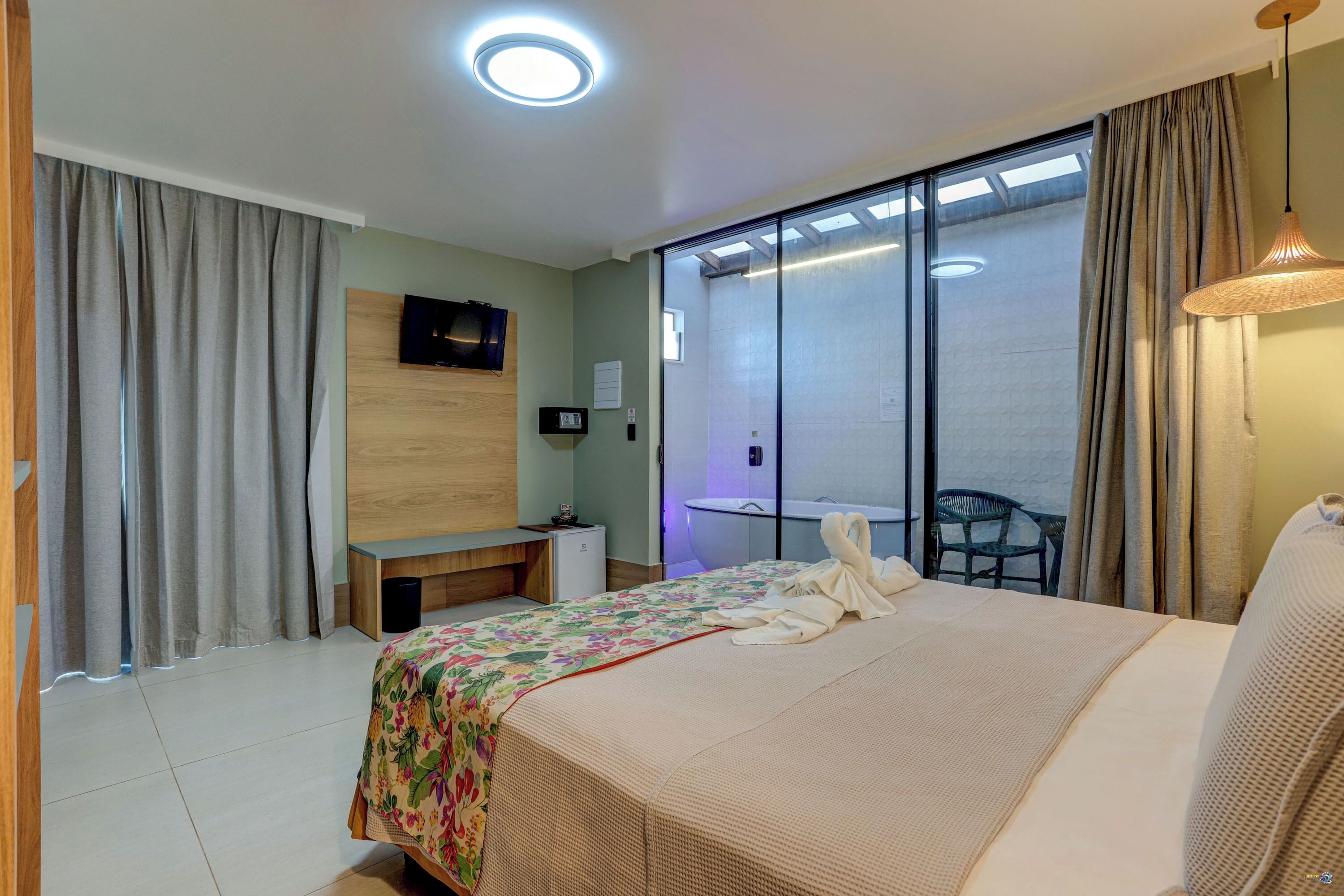 A hotel room with a bed, a TV, a desk, and a chair.