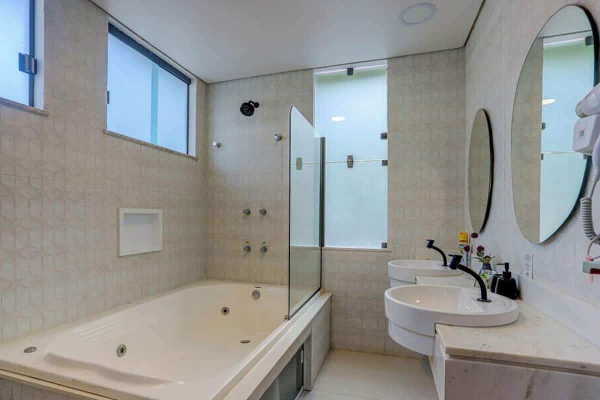 A modern bathroom with a glass-enclosed shower, a bathtub, and two sinks.