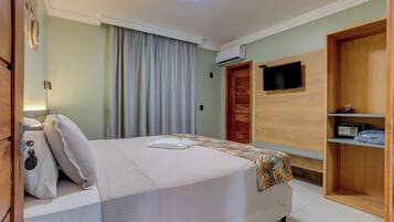 Une chambre d’hôtel équipée d’un lit, d’une télévision, d’un climatiseur, d’une armoire et d’une table de chevet.