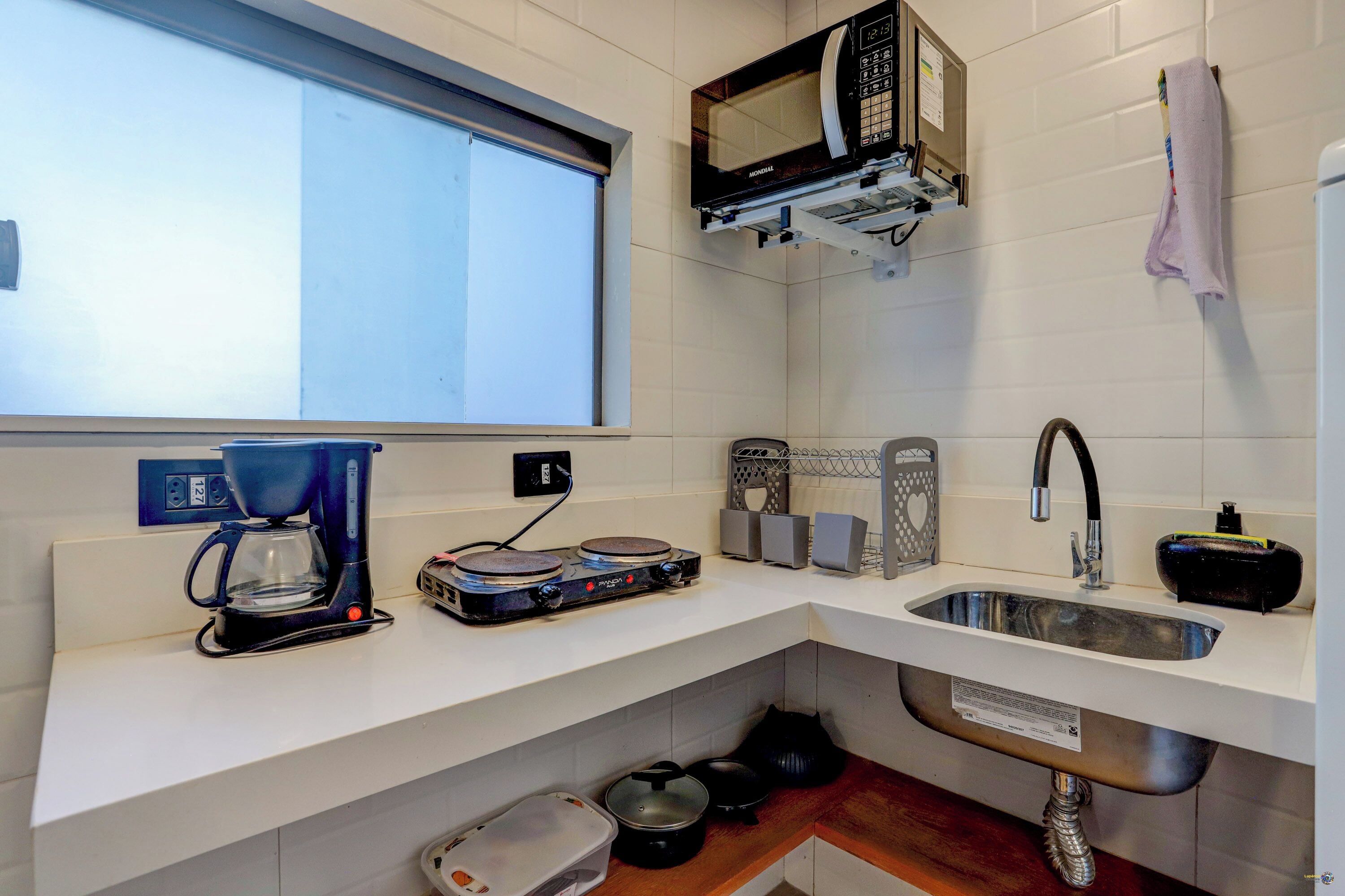 A compact kitchen with a coffee maker, microwave, sink, and various kitchen utensils.